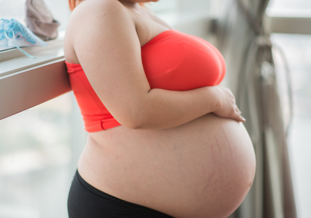 Happy mother Pregnancy belly skin close up sit on the bedの写真素材