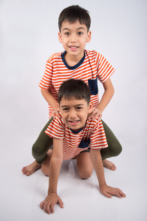 Little siblings boy brother smiling laying down together with happy face on white backgroundの写真素材