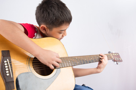 Little boy playing classic guitar on white background