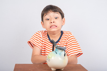 Little boy taking hammer trying to broke piggy bankの写真素材