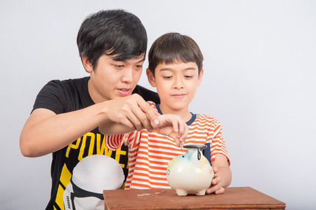 Asian teenager male sibling save the money into piggy bankの写真素材