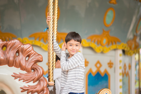 Little boy sitting in marry go round in amusement parkの写真素材