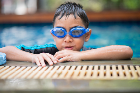 Little mix Asian Arab boy swimming at swimming pool in the hotel outdoor activityの写真素材