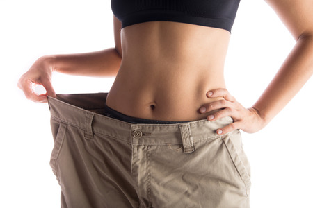 Woman wearing bigger pant after lose weight from work out excercise on white backgroundの写真素材