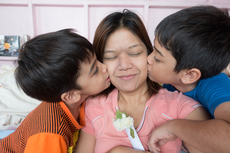 Little sibling boy give flower and kiss mom the loveの写真素材