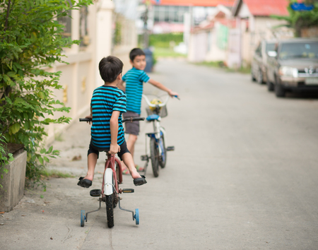 Little boy riding bicycle on the road around the houseの写真素材