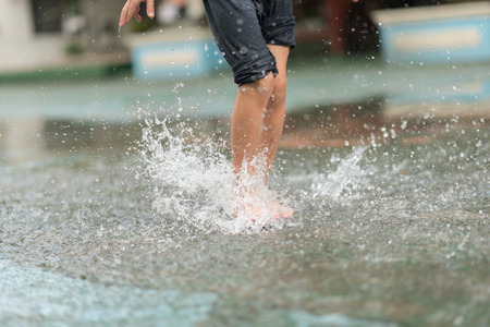 Little boy kicking ball in the water logging on the streetの写真素材