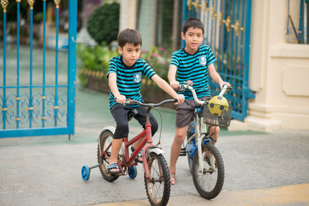 Little boy riding bicycle on the road around the houseの写真素材