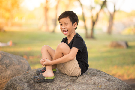 Little asian boy sitting on the rock in the park aloneの写真素材