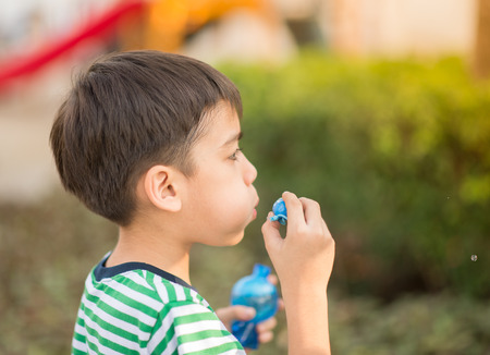 Little boy blowing bubbles soap in the parkの写真素材