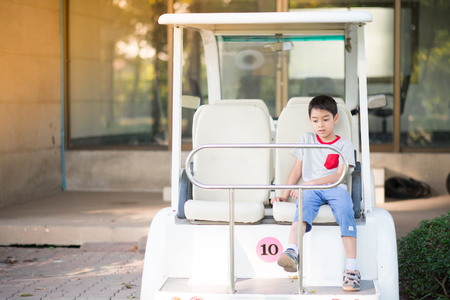 Little boy sitting behind the golf carts in the parkの写真素材