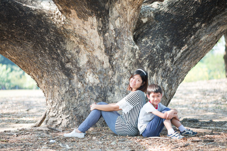 Mother and son sitting together under the treeの写真素材