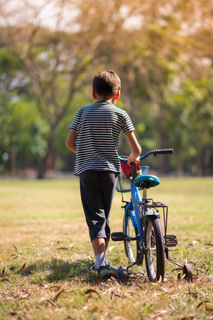 Litel boy walking with his bike in the parkの写真素材