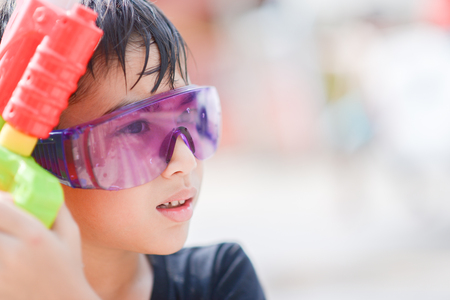Little boy playing water gun  splash in Songkran water festival in Thailandの写真素材