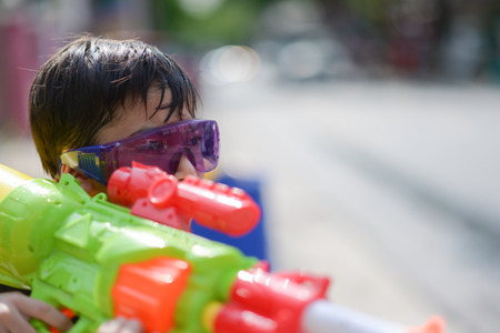 Little boy playing water gun  splash in Songkran water festival in Thailandの写真素材