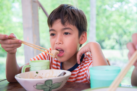 Little boy eating noodle at resturantの写真素材