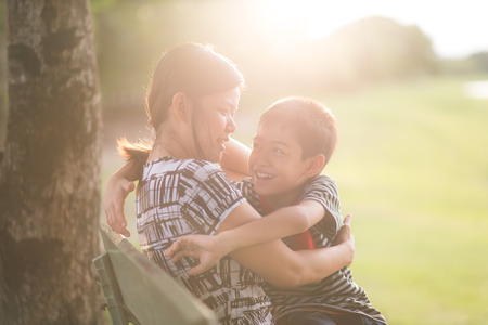 Single mother with son sitting together in the park sunset timeの写真素材