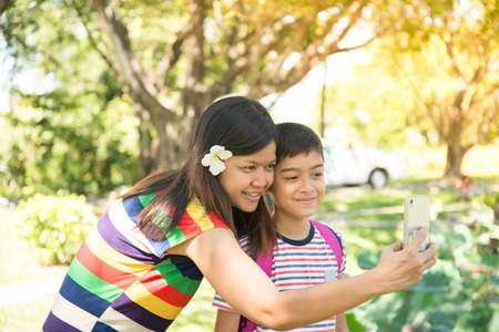 Asian single mom having fun with her sons together in the parkの写真素材