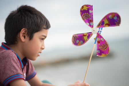 Little boy playing turbine wind toy at the beachの写真素材