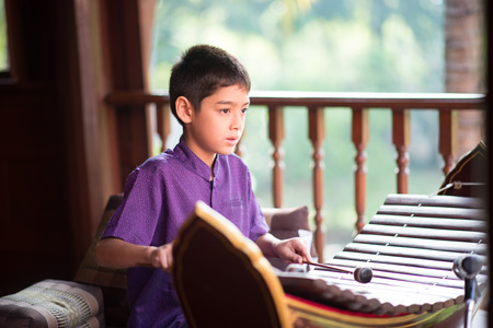Little asian Thai boy playing alto xylophone music performance in ceremonyの写真素材