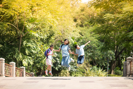 Mother and sons jumping together in the park summer timeの写真素材