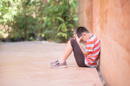 Little boy sitting alone with sad feeling の写真素材