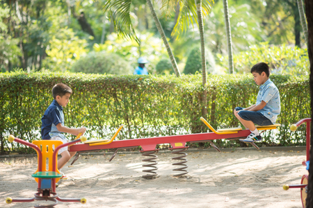 Little sibling boys playing seesaw at playgroundの写真素材