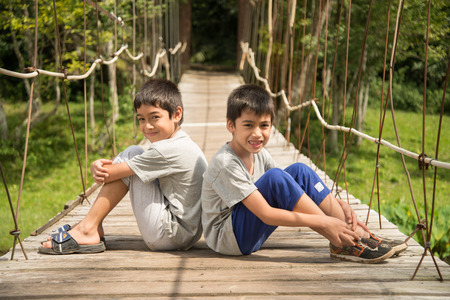 Little boy sitting together over the bridge outdoor activitiesの写真素材