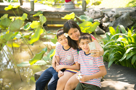Asian single mom having fun with her sons together in the parkの写真素材