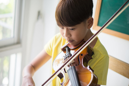 Little boys play and practice violin in the music class roomの写真素材