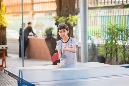 Kid playing table tennis outdoor with familyの写真素材