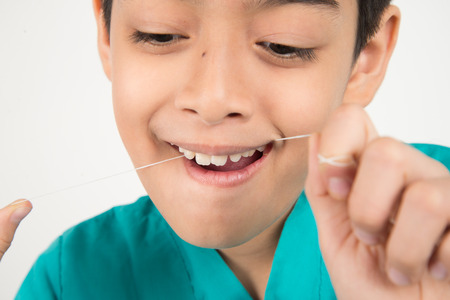Little boy using dental floss to clean tooth