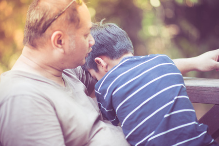 Father and son sitting and talking togetherの写真素材
