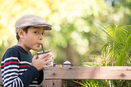Little boy drinking chocolate milk at green cafeの写真素材