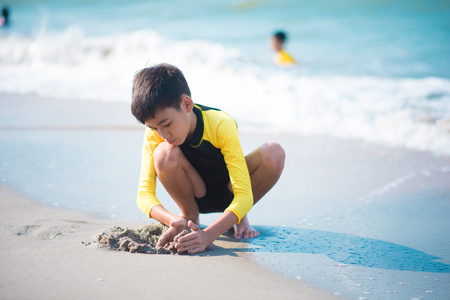 Boy playing wave and sand on the beachの写真素材
