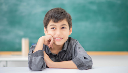 Student boy point to the chalkboard in the classroom