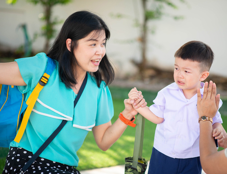 Little toddler boy cry, first day at school kindergarten with motherの写真素材