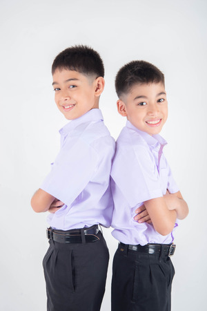 Little Asian sibling boys in student uniform pose together on white backgroundの写真素材