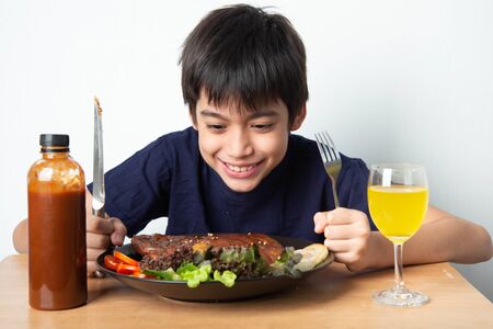 Little boy eating rib pork grill with happy face の写真素材
