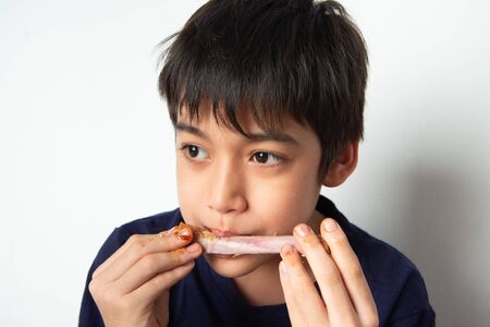 Little boy eating rib pork grill with happy faceの写真素材