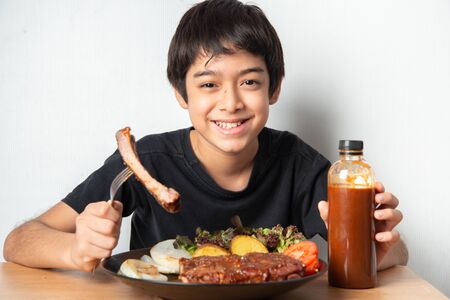 Little boy eating rib pork grill with happy face の写真素材