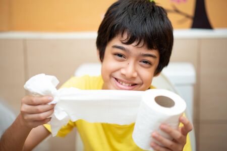 Little boy teen use tissue paper clean in toiletの写真素材