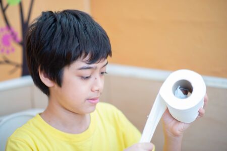 Little boy teen use tissue paper clean in toiletの写真素材