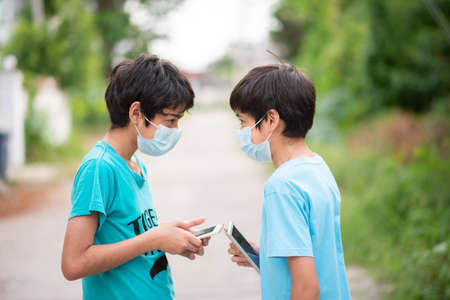 Happy Asian Family Walking In The Park Wearing Medical Face Mask with the phone in handの写真素材