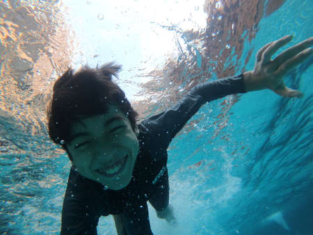 Little boy having fun playing underwater in the pool happy smileの写真素材