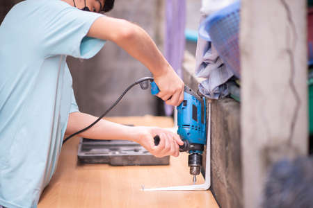 Boy teenager use screwdriver fix wood table