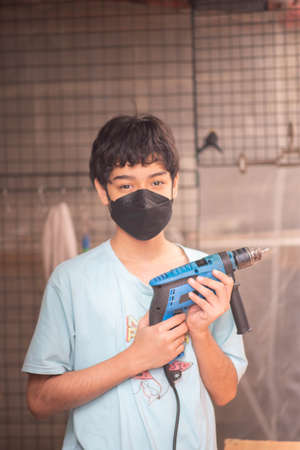 Boy teenager use screwdriver fix wood tableの写真素材