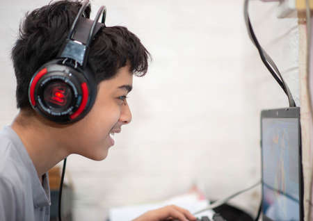 Teeenage playing computer game with headphoneの写真素材