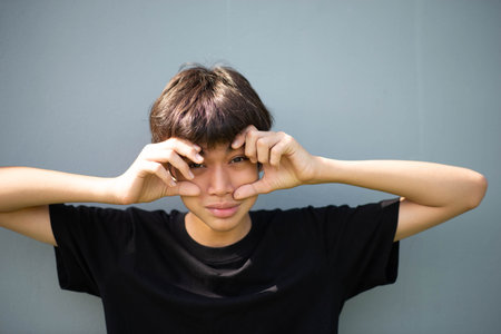 Teenage Boy's Expressions Collage: A captivating grid showcases a young Asian boy's diverse facial...