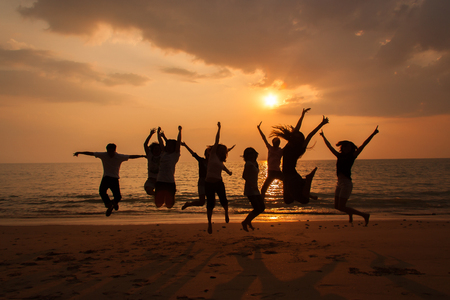 Silhouette photo of the team celebration on the beach at sunsetの写真素材